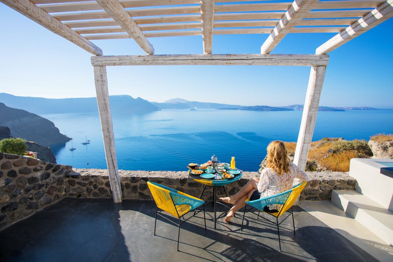 una mujer está desayunando desde su habitación de huéspedes con vistas a Santorini