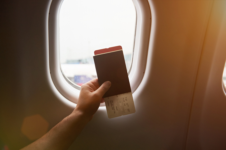 Passaporto tenuto davanti al finestrino di un aereo