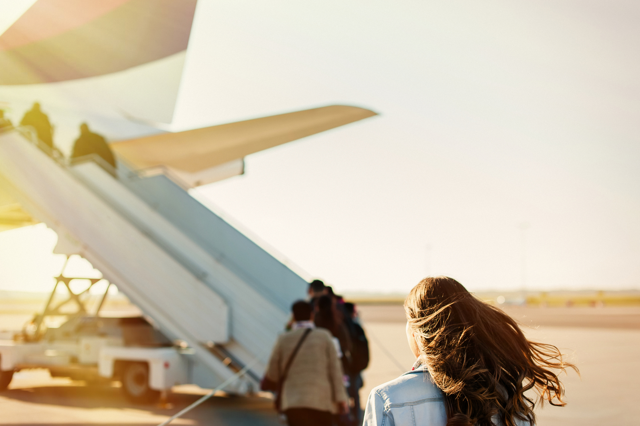 leisure-flight : young woman on tarmac boarding on a plane